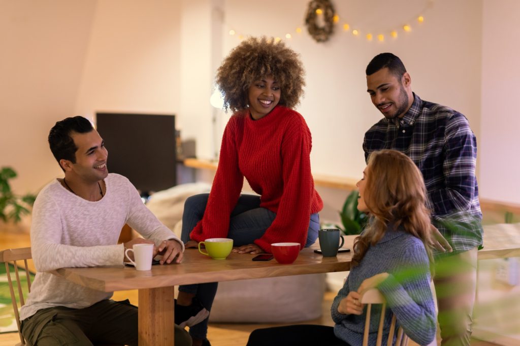 Millennial adult friends socialising together at home