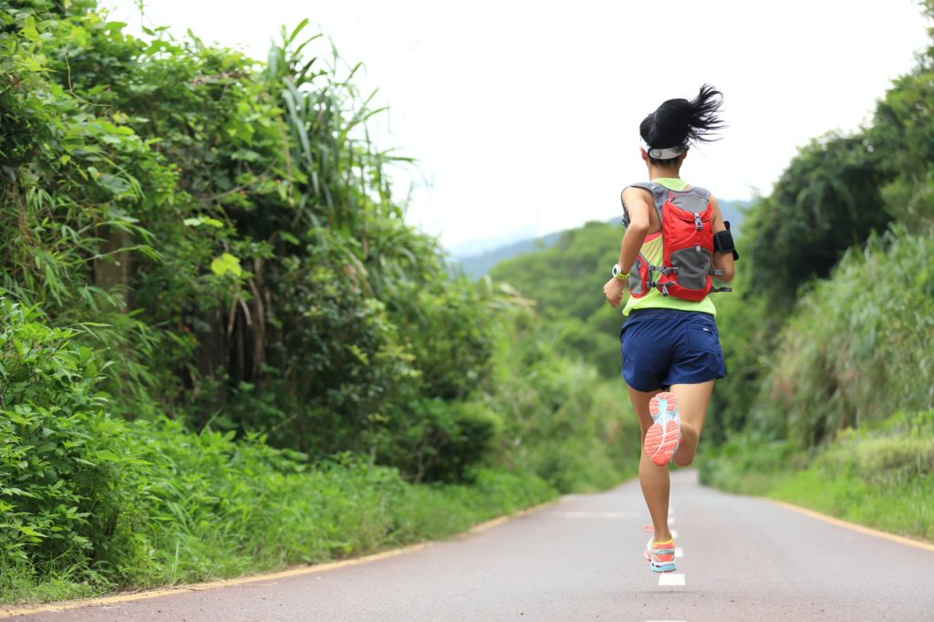 Runner athlete running on forest trail. woman fitness jogging workout wellness concept.